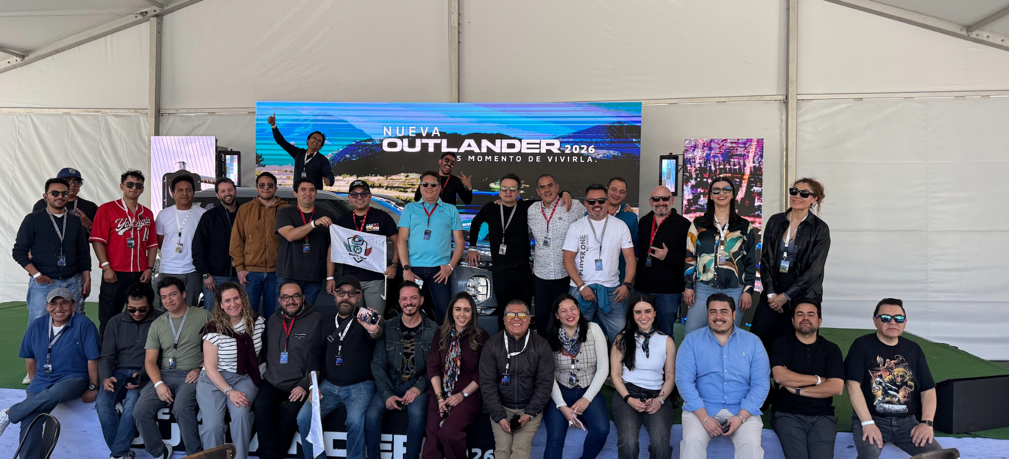 Foto grupal del equipo frente a la pantalla Outlander 2026