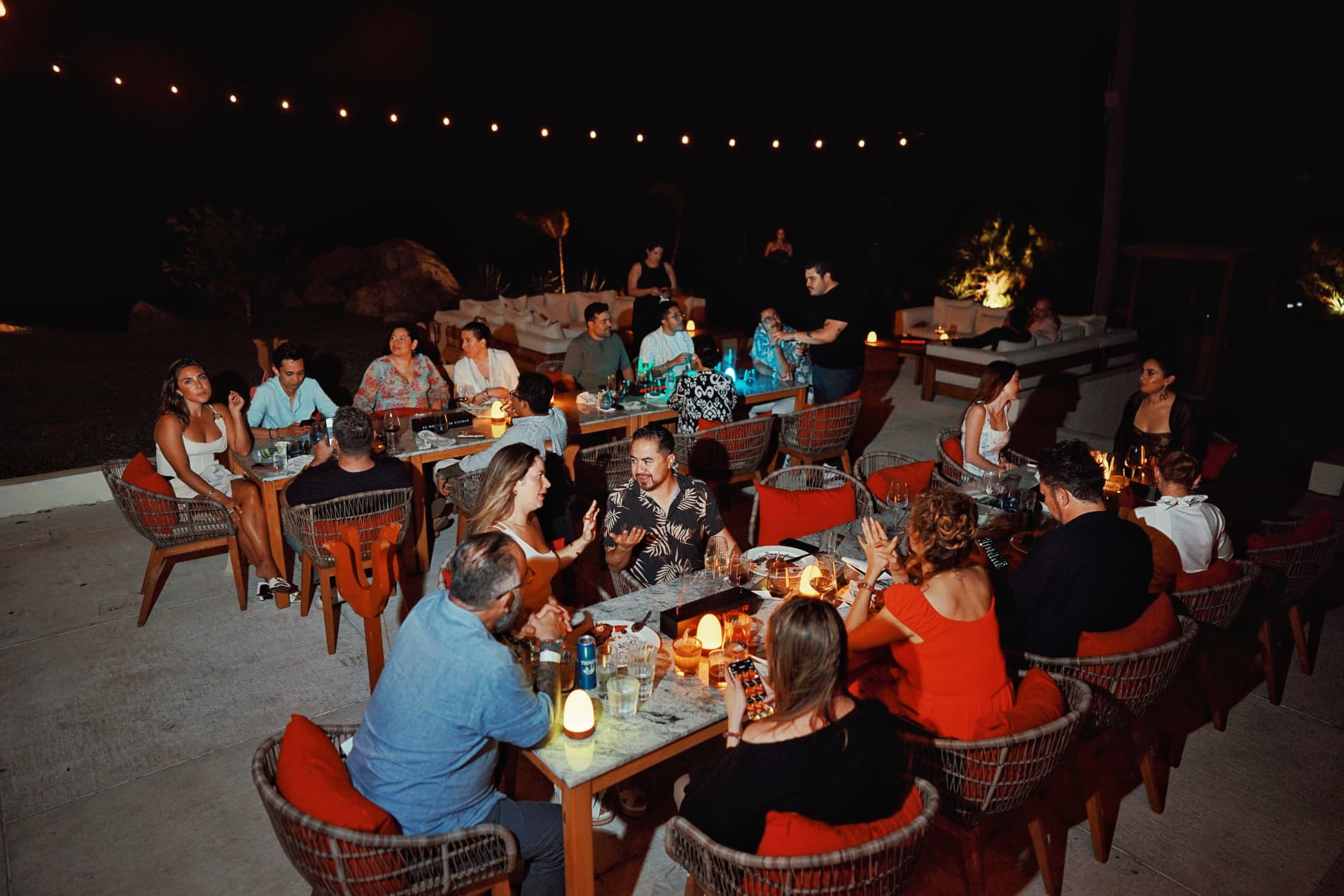 Cena al aire libre con invitados bajo luces colgantes