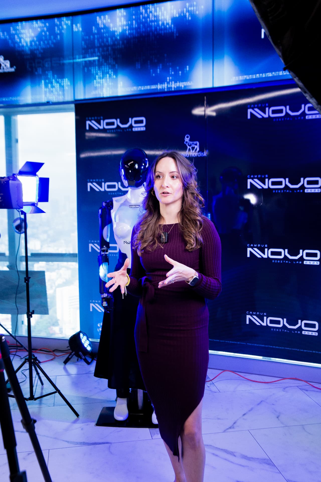 Presentadora frente al backdrop Campus Novo con robot humanoide