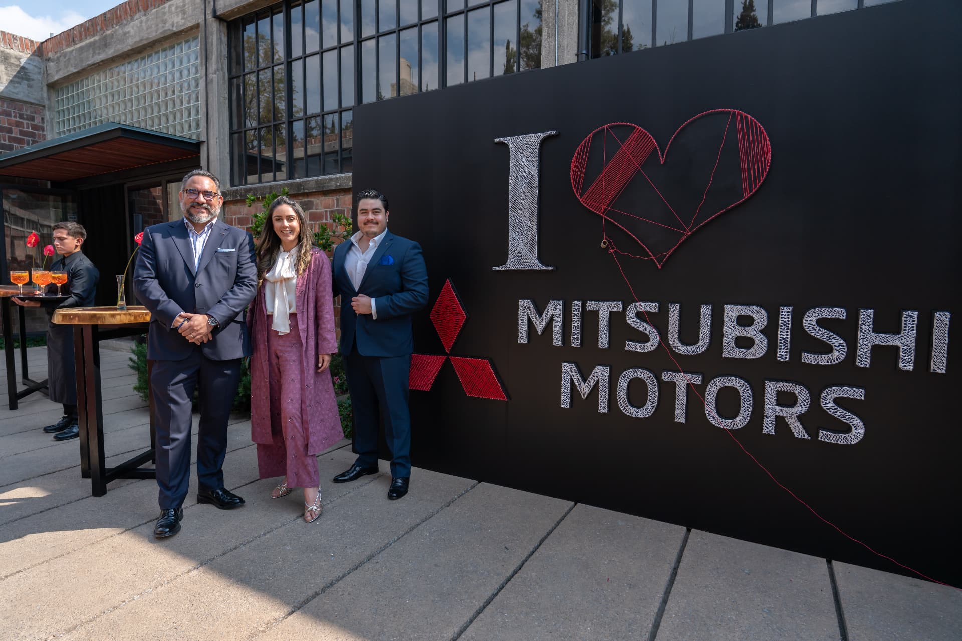 Directivos frente al mural de hilo Mitsubishi Motors